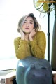 A woman sitting on top of a couch next to a fan.