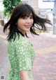 A woman in a green dress standing on a sidewalk.