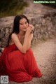 A woman in a red dress sitting on a dirt road.