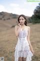 A woman in a white dress standing in a field.