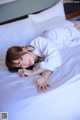 A woman laying on a bed in a white robe.