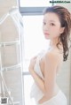 A woman in a white towel is taking a shower.