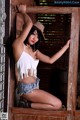 A woman in a cowboy hat leaning against a wooden door.