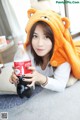 A woman in a bear costume holding a bottle of soda.